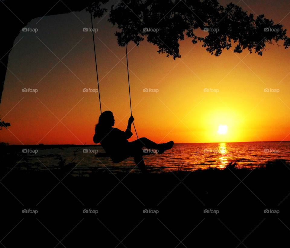 a girl swinging on a swing's silhouette 