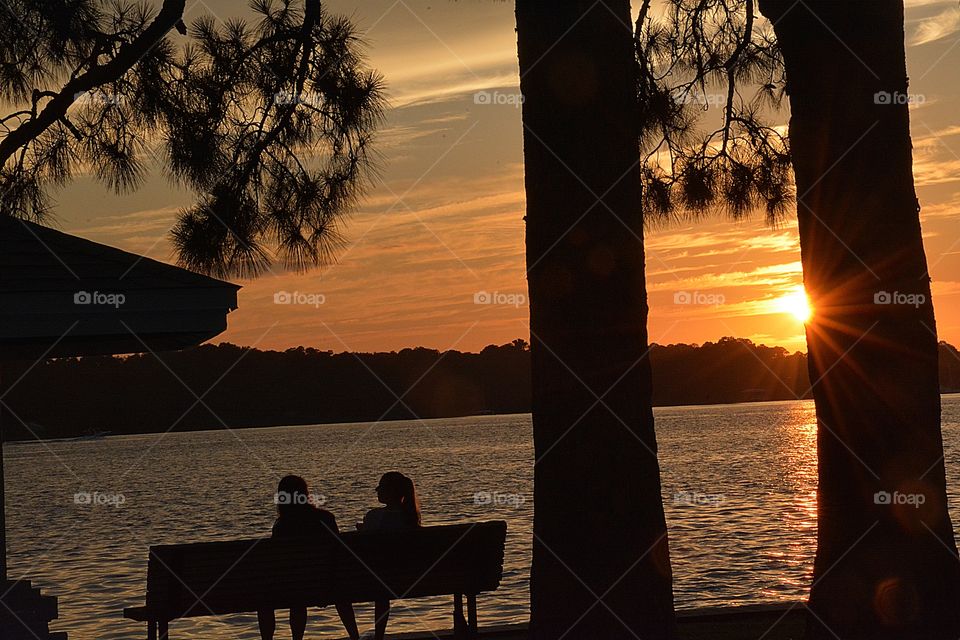 A loving mother and daughter sit on the bench discussing upcoming wedding plans. The close love for her daughter keeps their relationship close. 