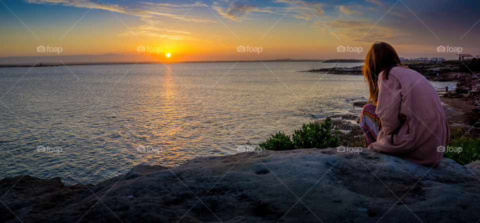 La Perouse, Sydney, Australia - October 10, 2015: Girl enjoying view of sunset. Overlooking the coastline is Frenchmans Bay, which leads to the Pacific Ocean. This venue is a very popular destination for tourists.