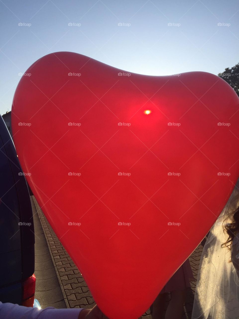 Big heart-shaped helium balloon against the sunlight.