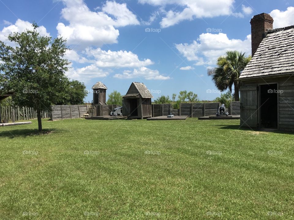 Courtyard of Fort King George, showing a Sentry tower, munitions shed, canon placements, embankment wall, and edge of barracks.
