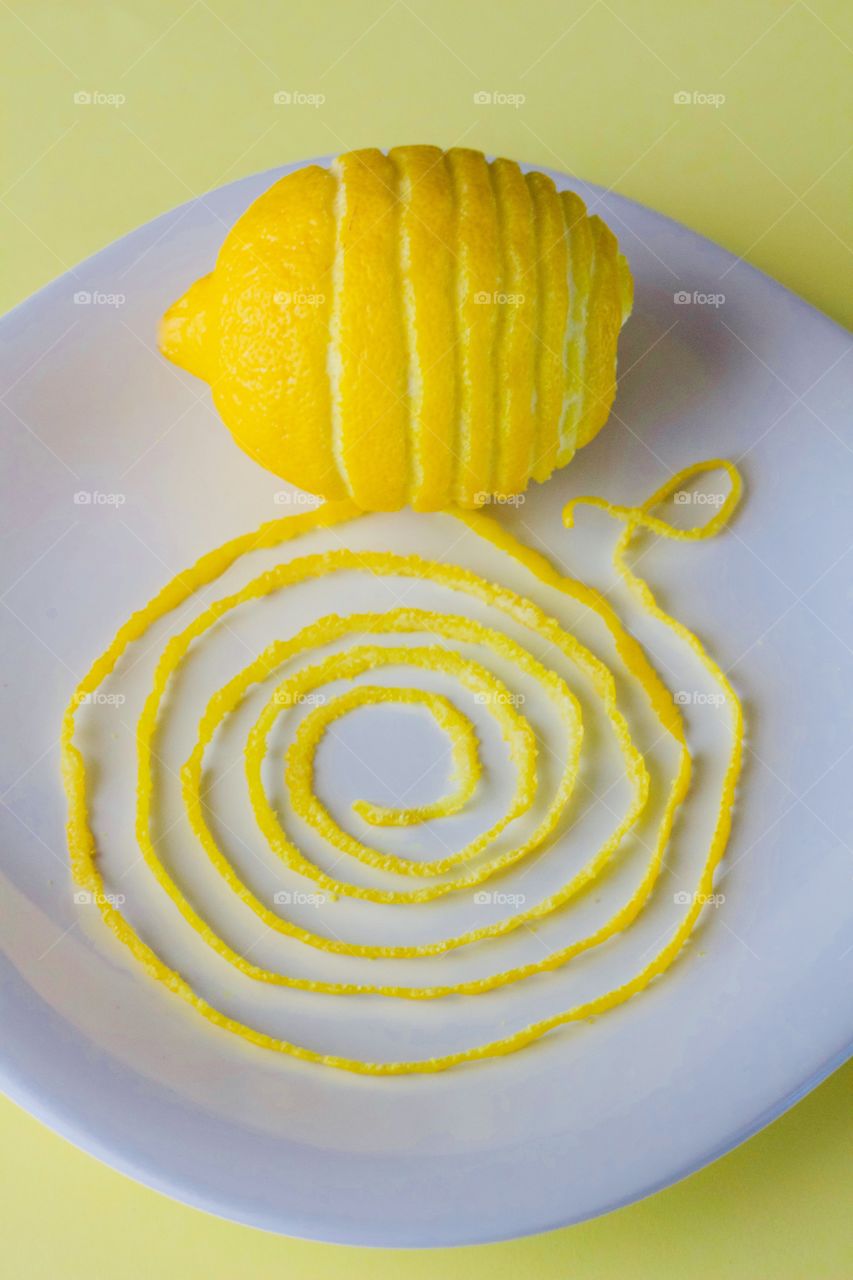 Fruits! - Lemon and spiraled lemon peel on a white plate with yellow background  