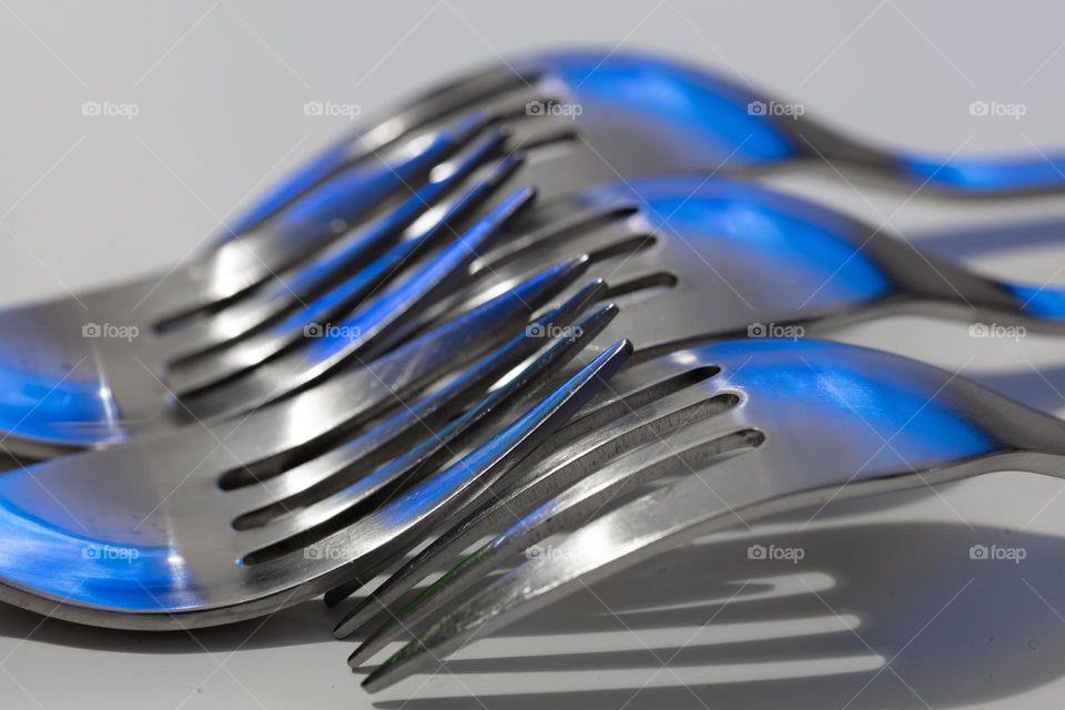 blue rays of light reflecting in many forks close up