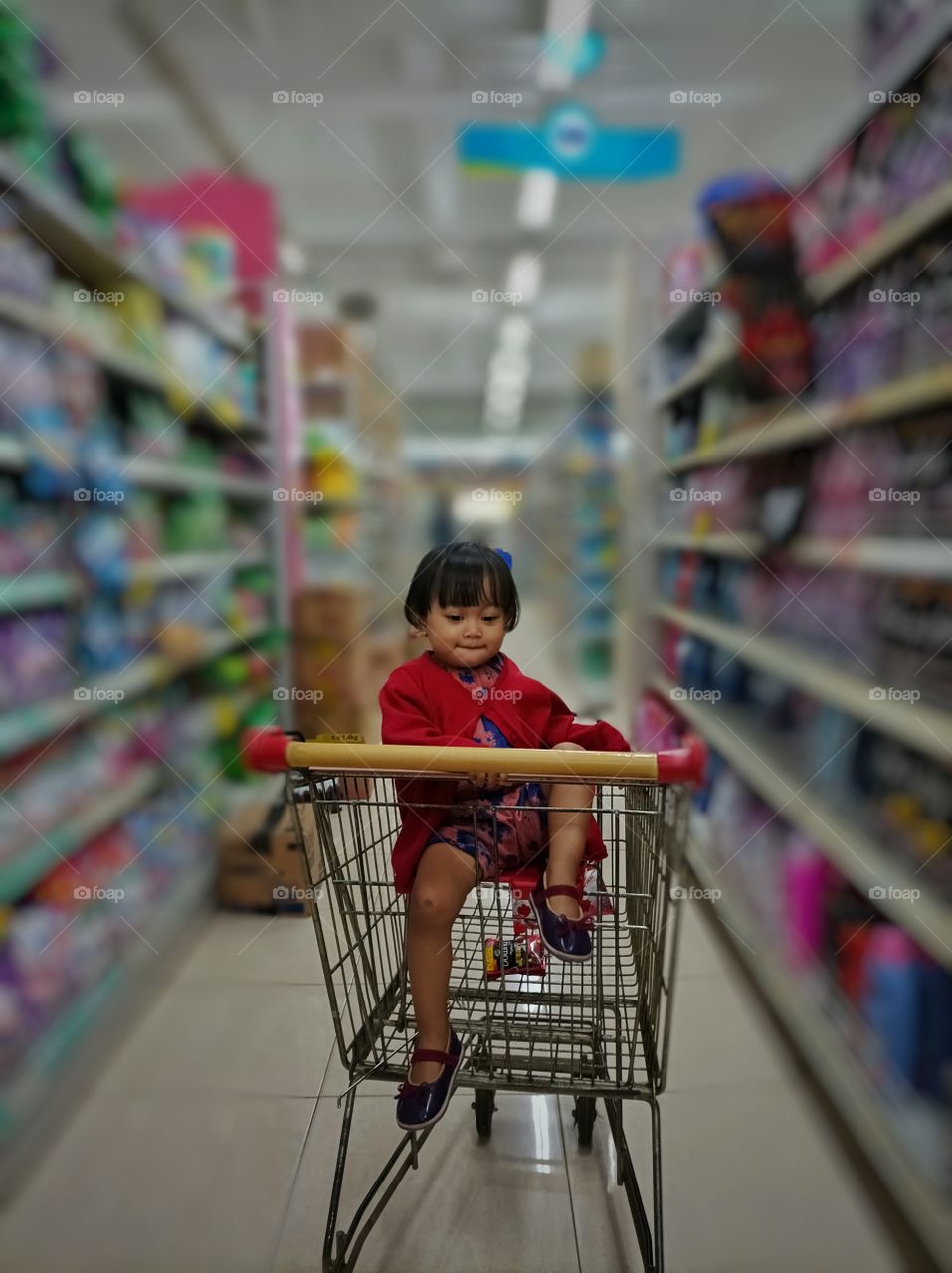 an happy baby girl sitting on a shopping cart.