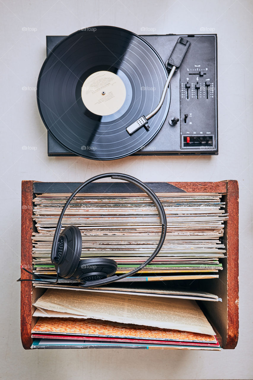 Stack of black vinyl records, turntable vinyl player and headphones. Classic stereo set. Candid people, real moments, authentic situations