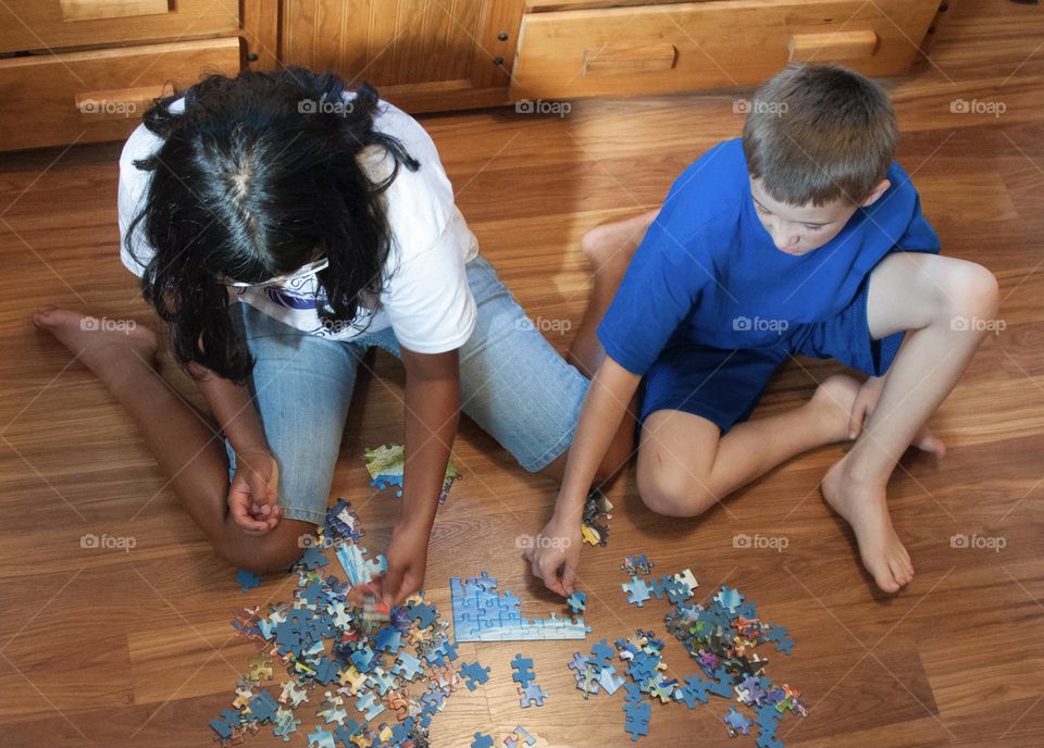 Brother and sister putting puzzle together 