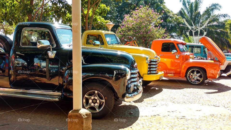 Exposição de Picapes/pick ups de cores laranja, amarela e preta, em evento de colecionadores. Carros tuning.