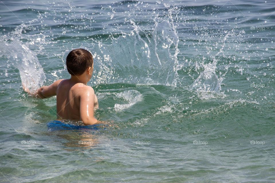 Back view of boy playing at the sea