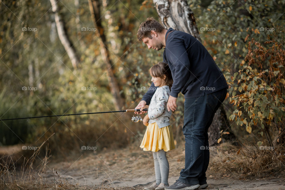 Family fishing on a lake at autumn day 