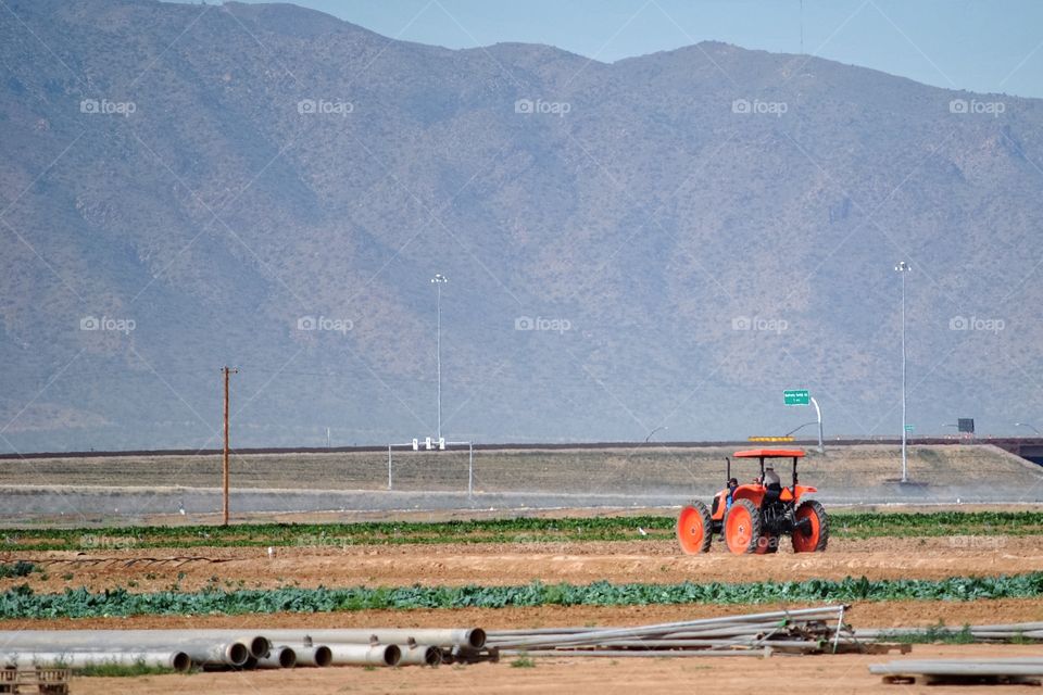Red tractor dwarfed by mountain 