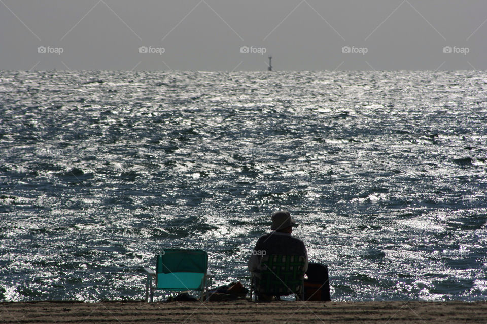 Husband waits for wife looking out peacefully to sea in Melbourne