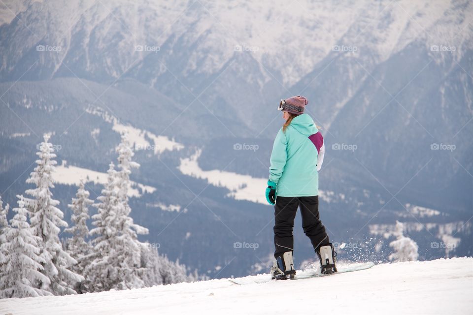 Young woman snowboarding in peak Postavarul 