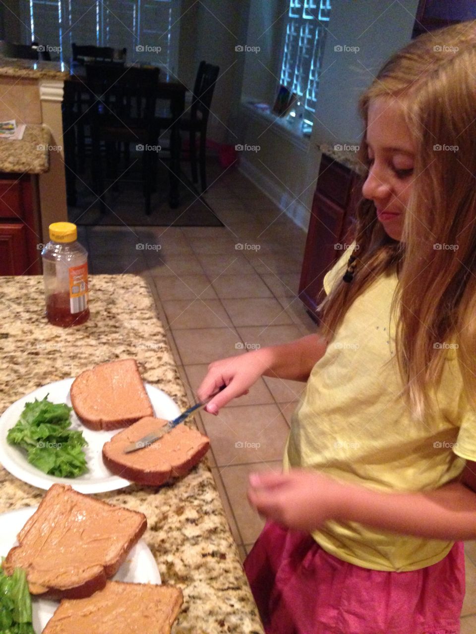 Hunger wins. Girl making a peanut butter and honey sandwich