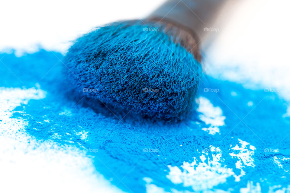 product - blue powder with make up brush on a pure white background. Close-up macro image