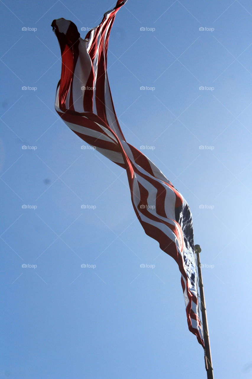 This is a picture of an American flag looking at it from underneath and flying high in the sky.