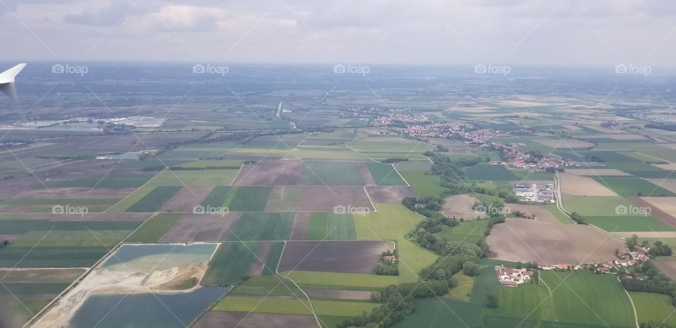 Window view from flying plane of beautiful nature, shades of green, fields of grass and farm land