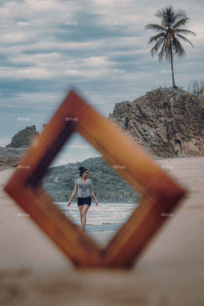 Girl's reflection in a mirror in the middle of the sand on the beach