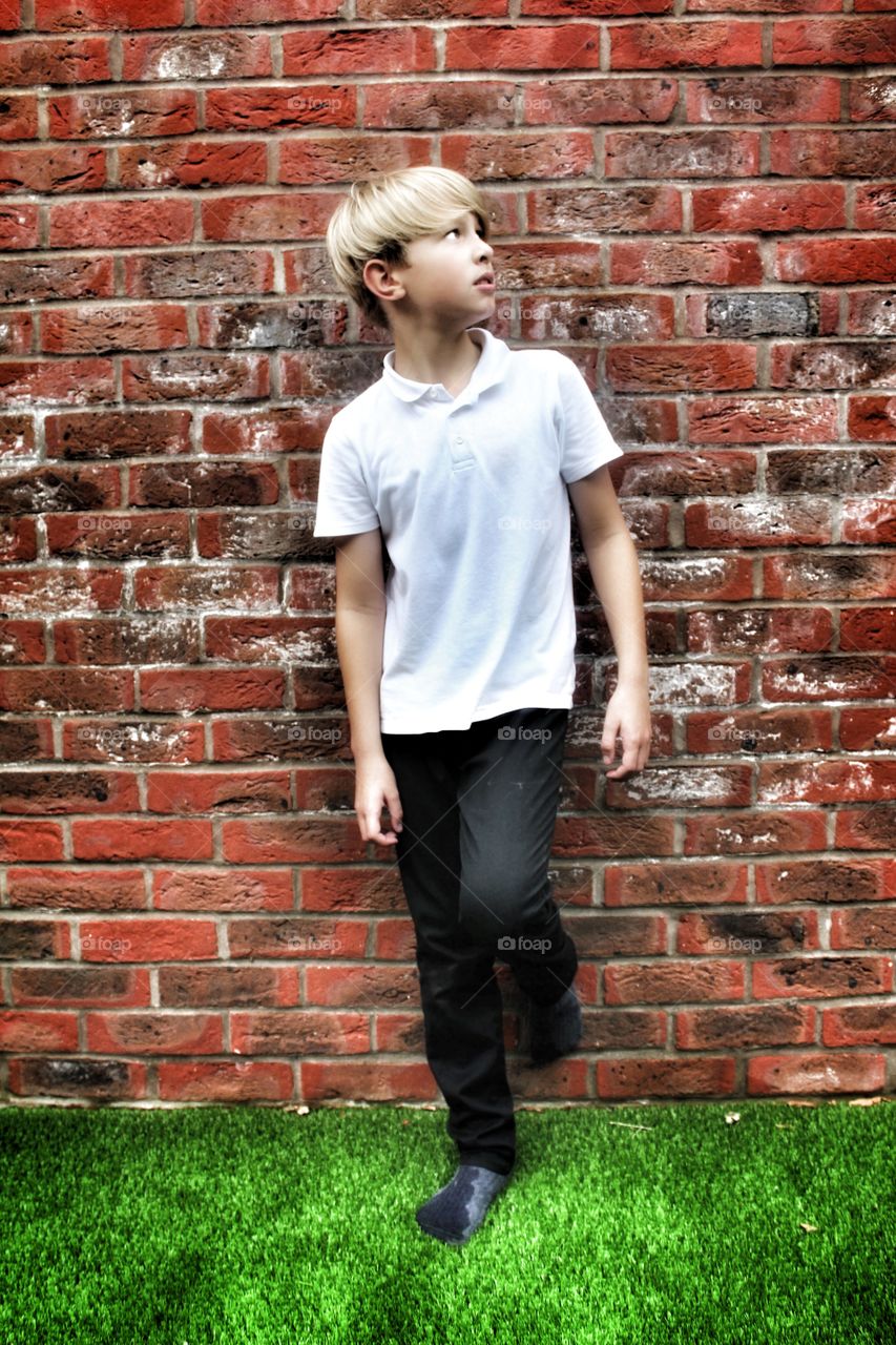 Boy chilling against a brick wall