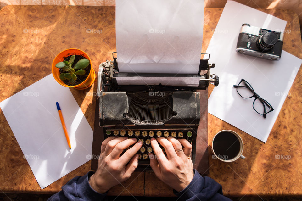 A young writer is writing a new book on an old typewriter.