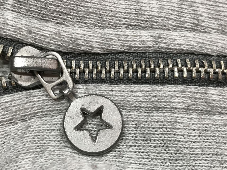 Metal zipper with a star on a gray sweatshirt.