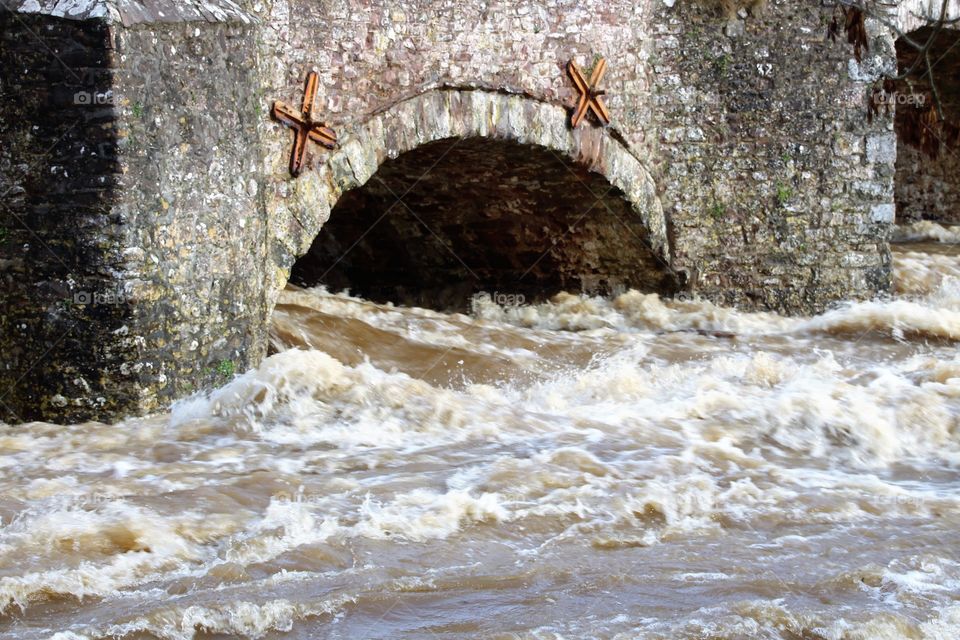 Rising waters gushing through one of the arches of Bickleigh bridge. A few metres away the gardens of nearby homes and hotel are flooded!