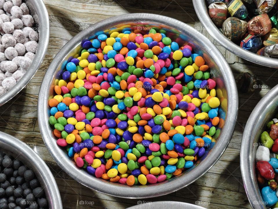 Group of small red, yellow, green, blue, brown and orange coated chocolate candies, top view