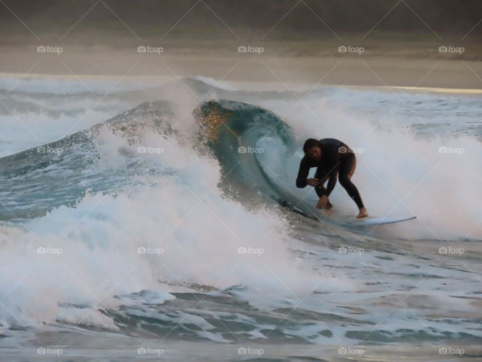 Summer by the ocean: surfer surfing a barrel wave at sunset on the Australian coast.