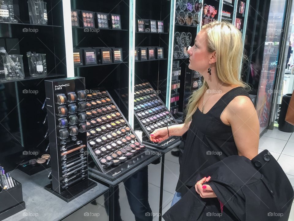 Woman 30 plus years is lookng at makeup products in a taxfree shop at Copenhagen airport in Denmark.