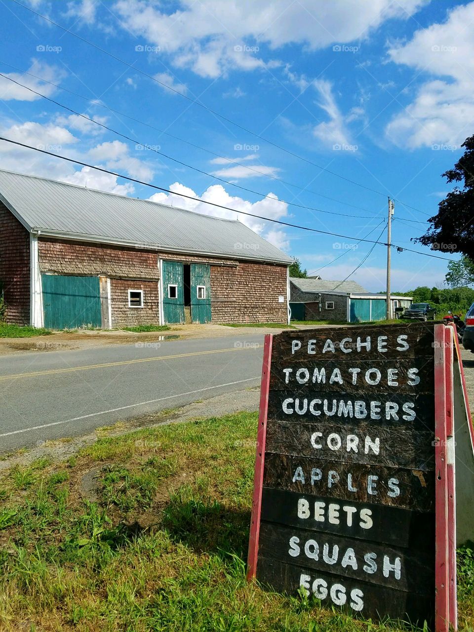 Roadside Stand, old barn across the road, sign for veggies standing.