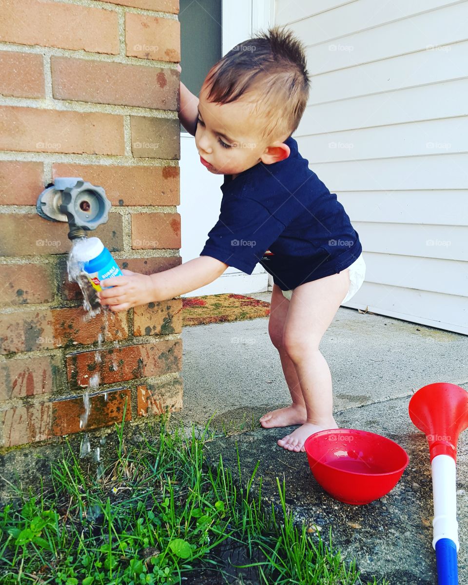 Boy playing with water outside the house