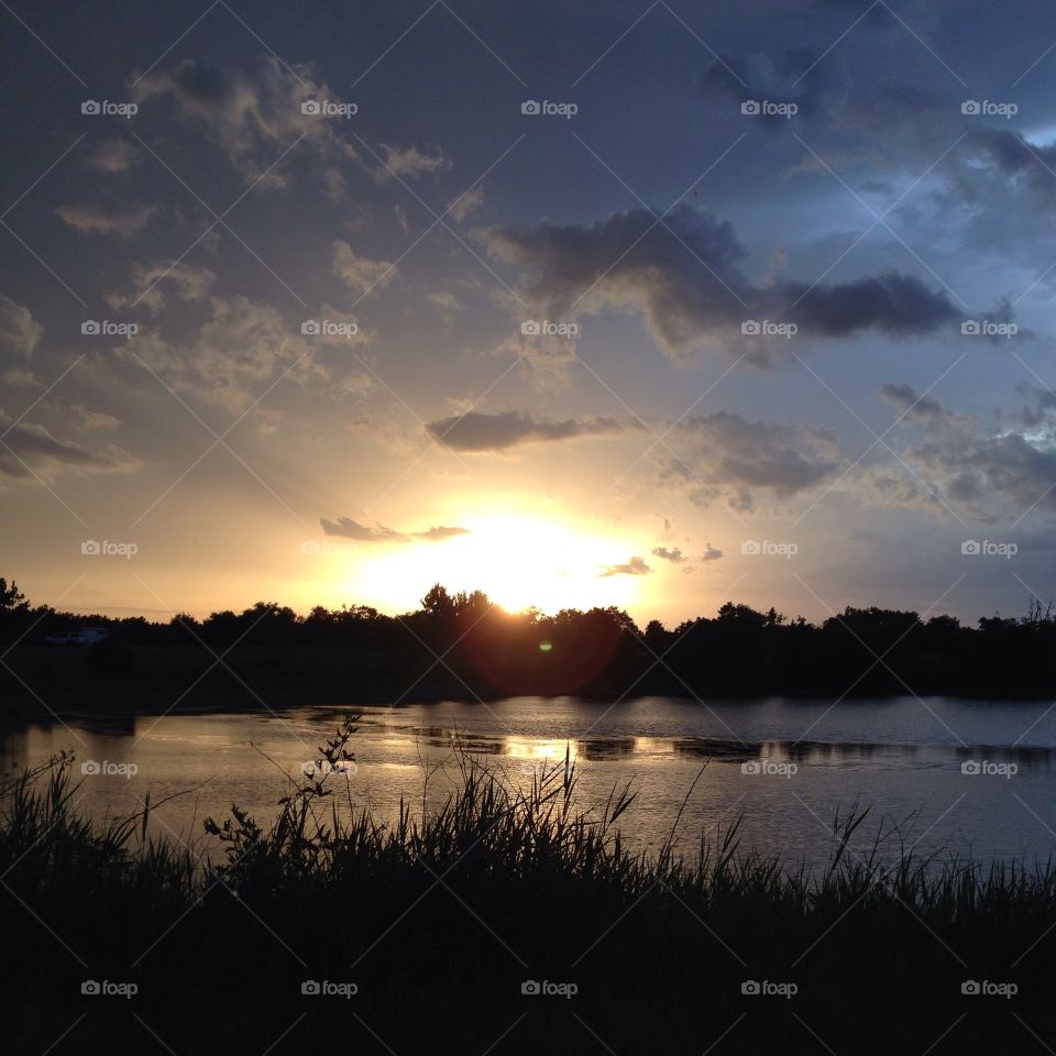 Sunset over a pond.  . This is the sun setting as a thunderstorm was moving in from the east.  