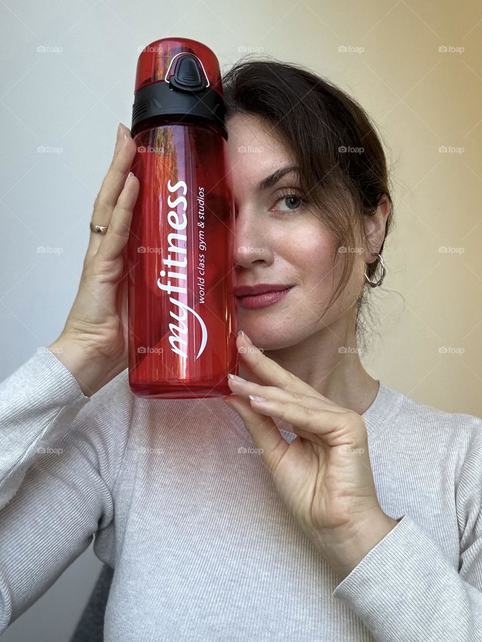 Woman’s portrait with product, showing a fitness bottle in her hands