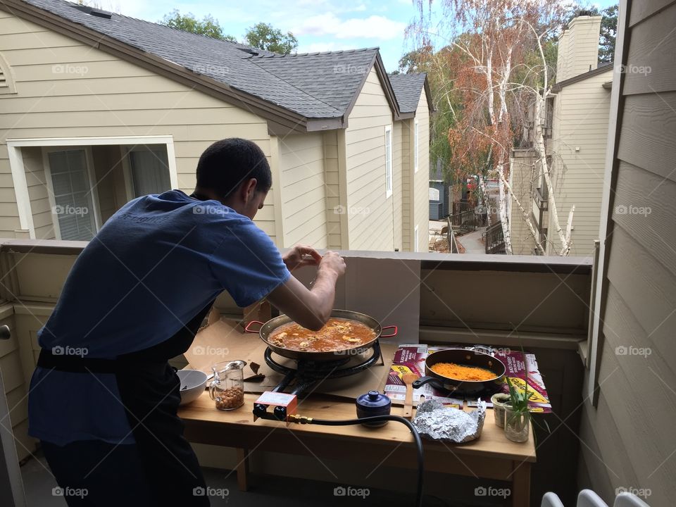 Guy cooks paella on the balcony of his apartment
