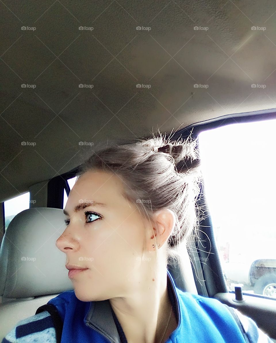 woman in car with head turned to the side stares intently