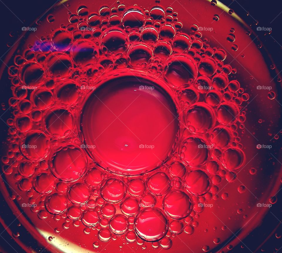 Red oil bubbles in the glass of water