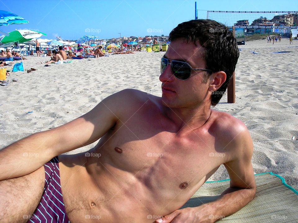 Young handsome Man taking sunbathe on sand 