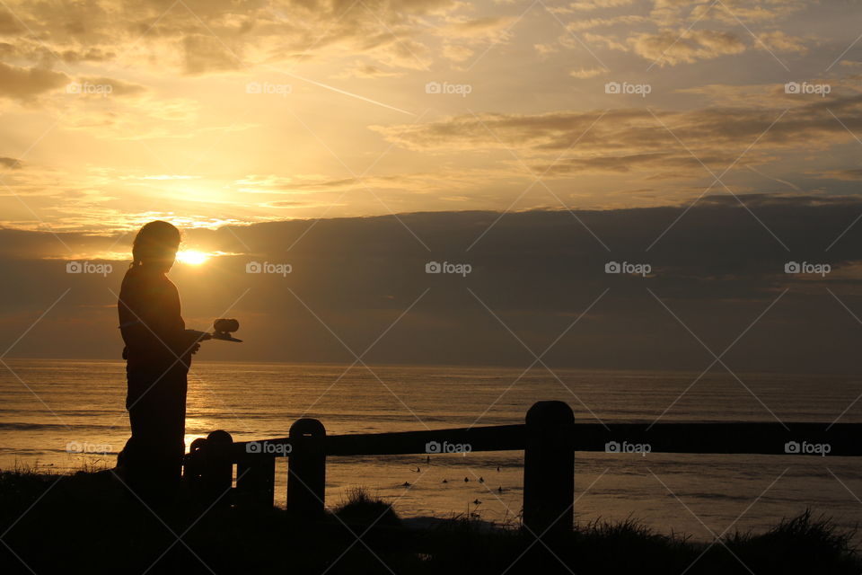 Little girl with skate board watching sunset landscape 