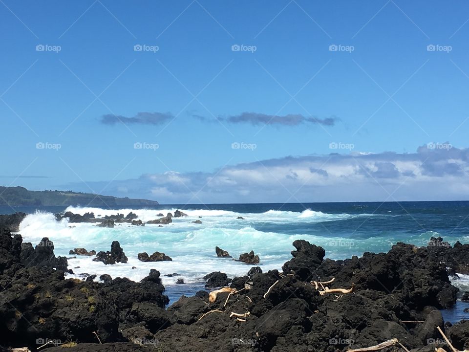 Gorgeous ocean with waves breaking and sea rocks in the foreground on the Road to Hana in Maui, Hawaii.