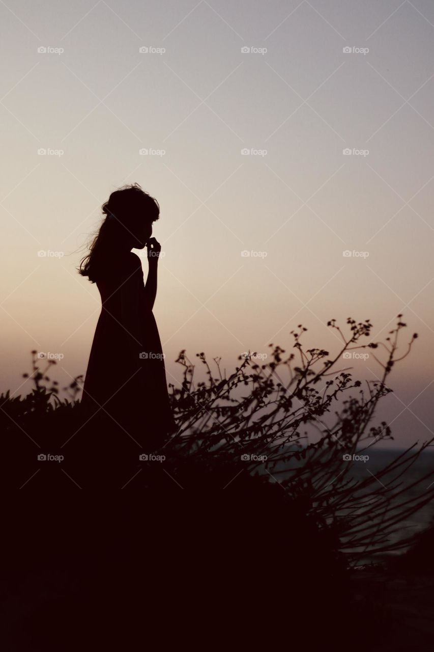 Silhouette of a girl on the hill by the sea 