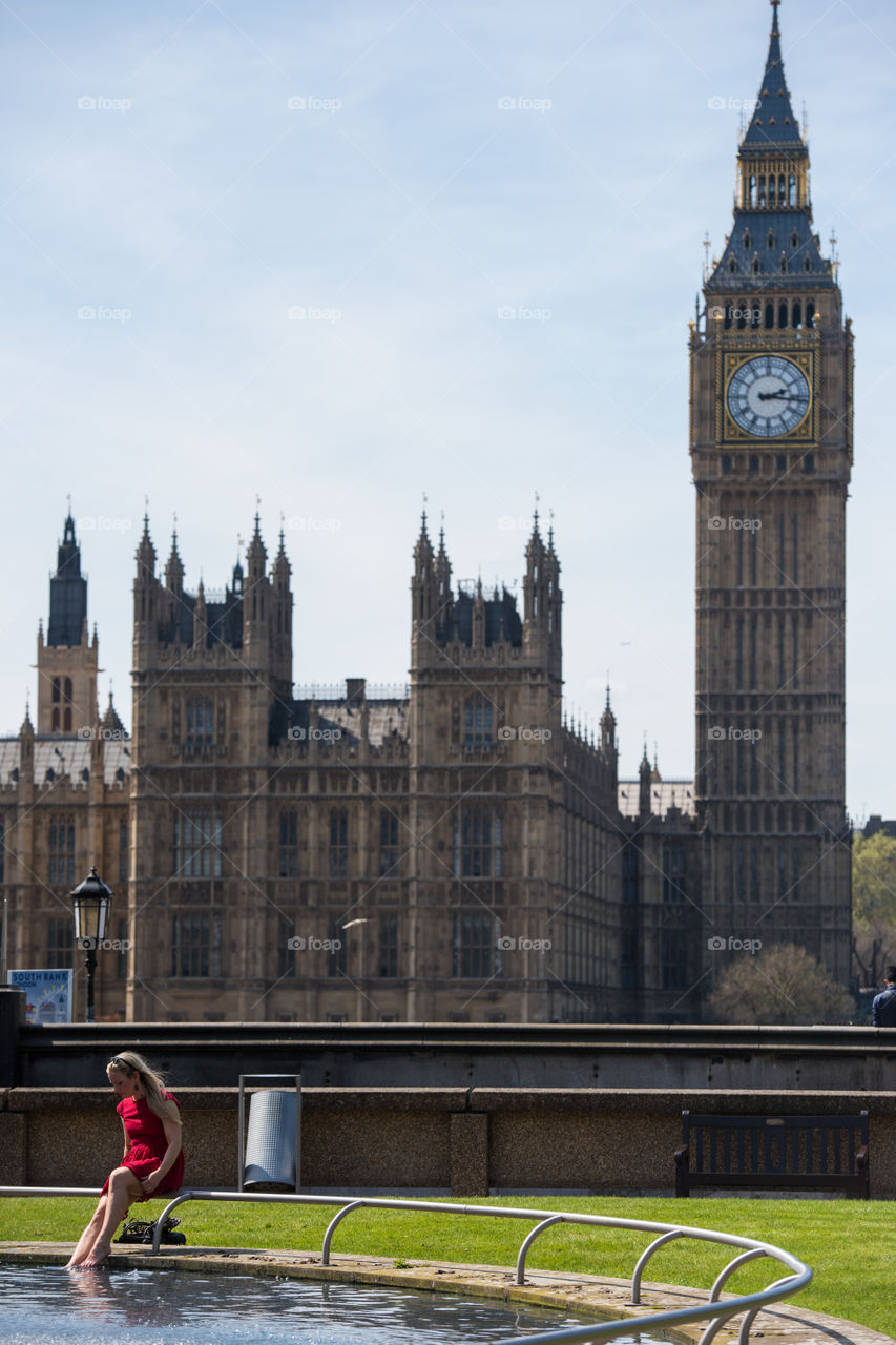 Woman (tourist from Sweden) bathing her feets in a park (at the hospital park) near Big Ben in London.