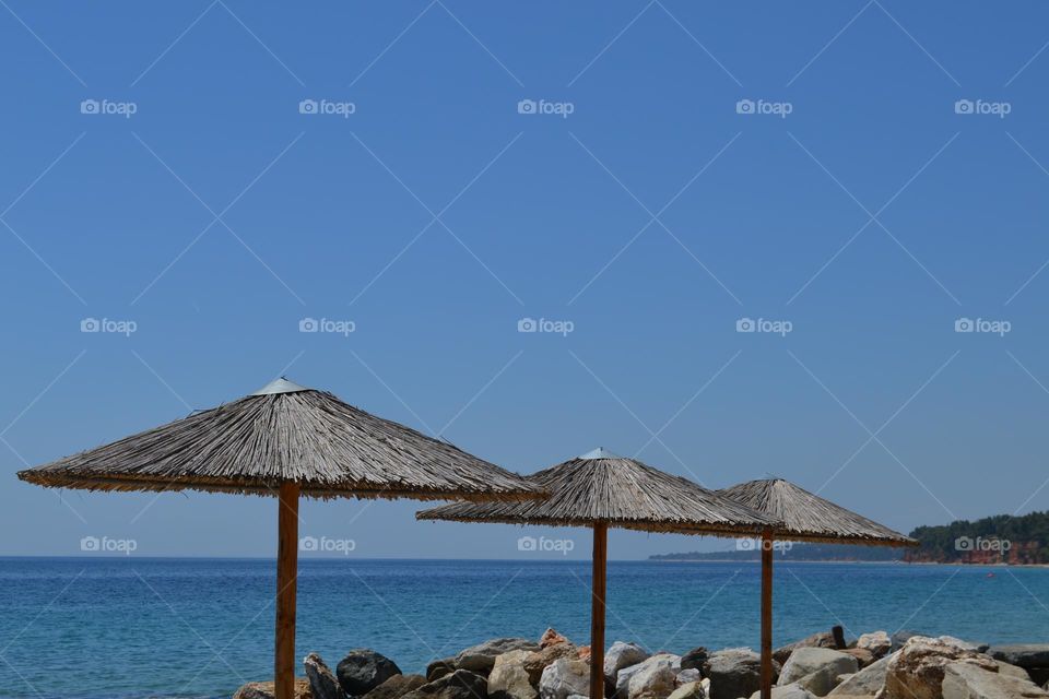 Umbrellas on the beach are triangular and endless blue sea in the background