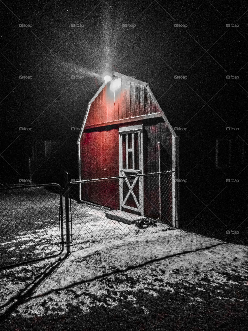  During a snowy night, with a mysterious look and a hazy light shining, this classic barn stands. 