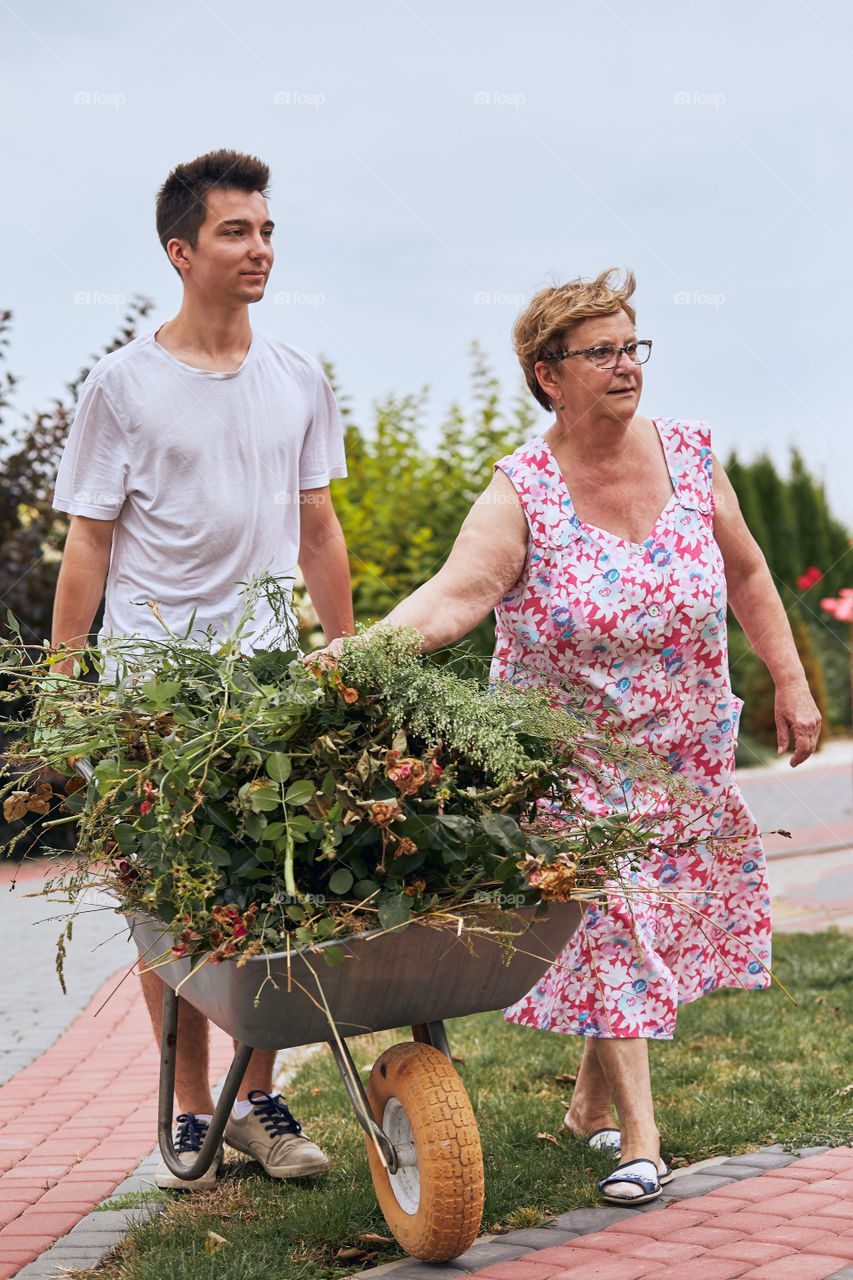Grandchildren helping grandmother at a home garden. Candid people, real moments, authentic situations