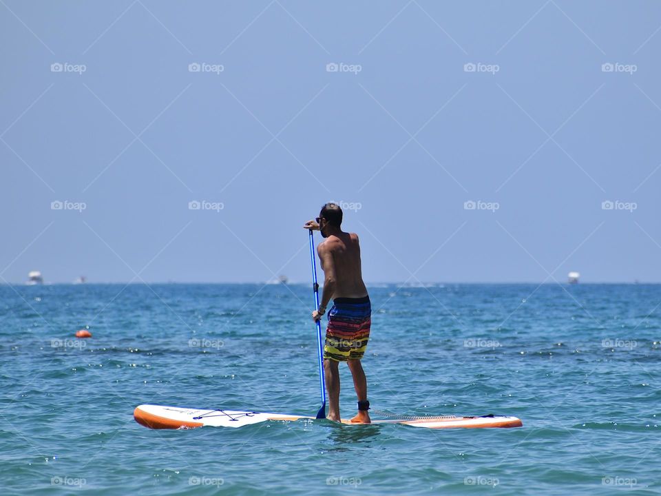 Men with paddle surf at the sea