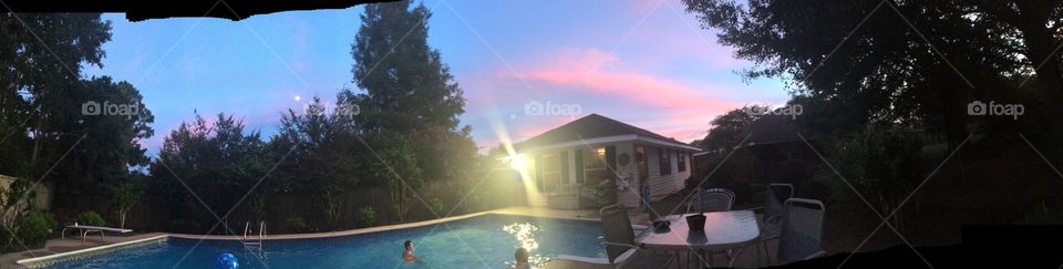 A nice panoramic view of our pool house in the evening with pink clouds and clear water. 