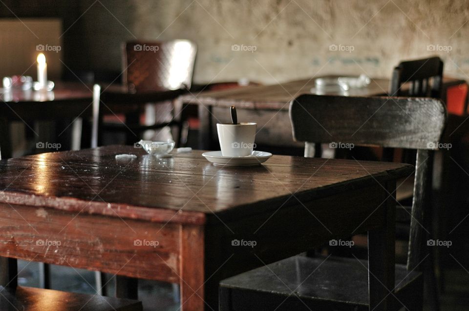 Coffee on wooden table in cafe. White coffee cup standing on wooden table in cafe