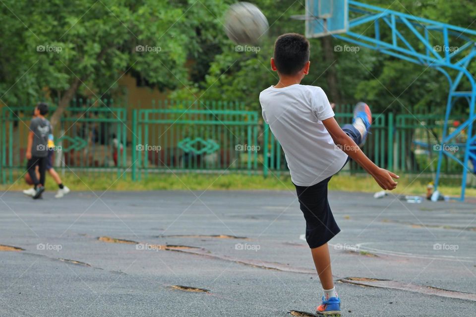 children in the old stadium playing football. moment of hitting the ball