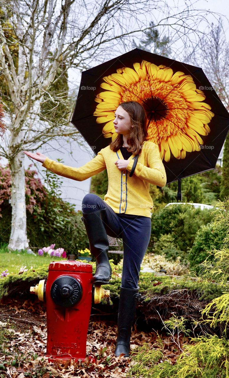 Girl under big umbrella checks for rain drops 