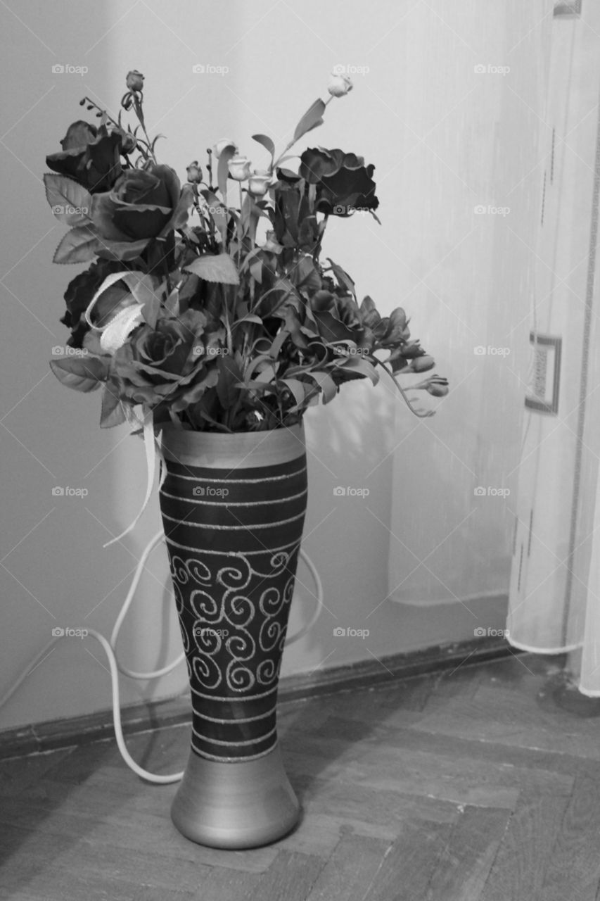 Black and white artificial roses and flowers in a tall vase indoors