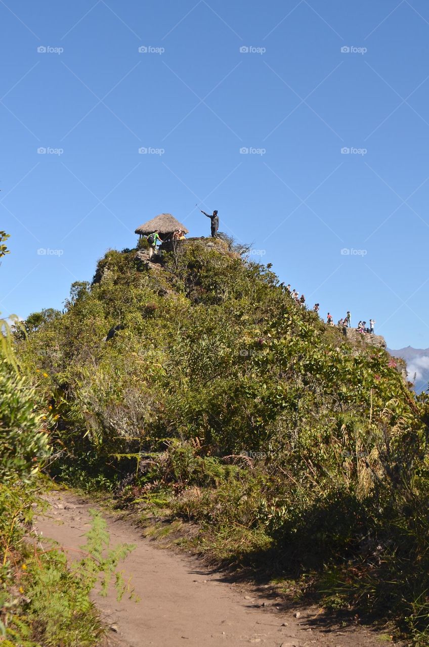 First glimpses of Machu Picchu mountain top and nature views, with many hikers and their cameras and selfie sticks. 